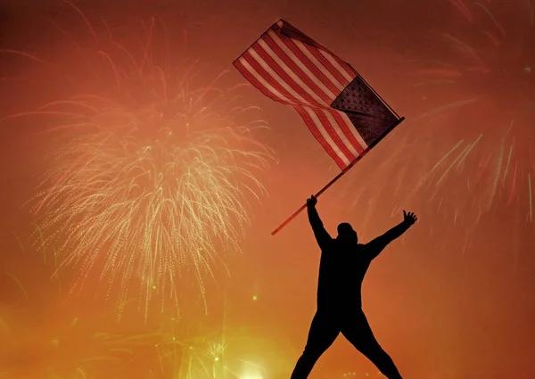 七月四日举着美国国旗跳爱国者女孩的轮廓 爱国节假日快乐的年轻人拿着美国国旗看着烟火 美国庆祝七月四日 — 图库照片