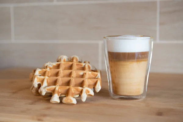 Glazen kopje gelaagde koffie met mini-stroopwafel, syrupwaffles cookies op de lichtgrijze achtergrond met kopie ruimte — Stockfoto