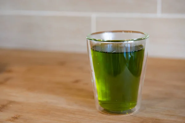 Tazza di tè verde e brocche o barattoli di vetro sul tavolo di legno — Foto Stock