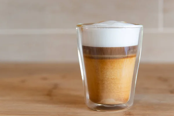 Multilayer coffee or cappuccino in a glass cup on wooden table — Stock Photo, Image