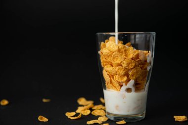 Siyah arkaplana karşı şeffaf bir camda mısır gevreği.