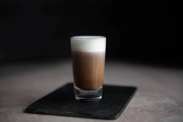 Mini csésze cappuccino egy pohár pohár fekete háttér és könnyű asztal — Stock Fotó