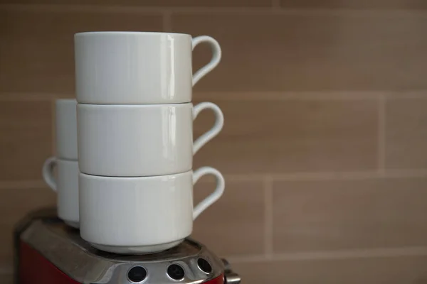 Tazas de café blanco de pie uno encima del otro contra una pared gris — Foto de Stock