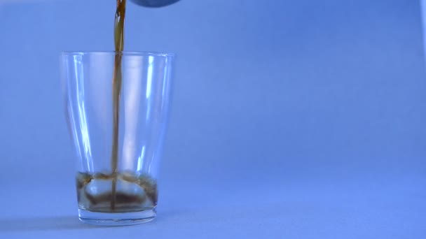 Black coffee poured into a transparent glass on an isolated blue background — Stock Video