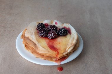 Balla doldurulmuş ince krep yığını ve taze yaban mersininin yan görünüşüyle süslenmiş seçici odak noktası ve fotokopi alanı olan açık arkaplan