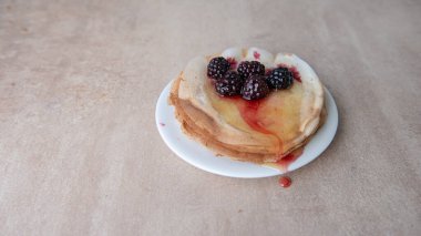 Balla doldurulmuş ince krep yığını ve taze yaban mersininin yan görünüşüyle süslenmiş seçici odak noktası ve fotokopi alanı olan açık arkaplan