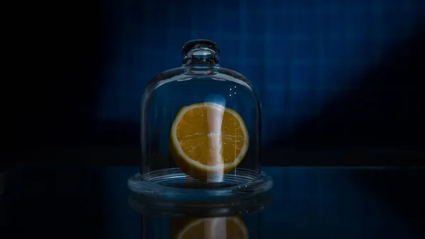 Medio limón en un recipiente de almacenamiento de limón de vidrio sobre un fondo azul oscuro — Foto de Stock