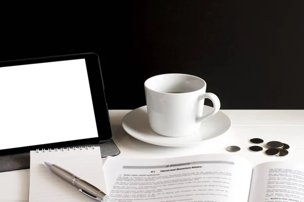 Eine Tasse Kaffee, Tablet, Datenbuch, Notizblock, Münze und Stift auf weißem Holztisch. — Stockfoto