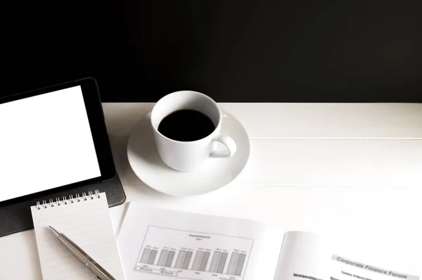 Eine Tasse Kaffee, Tablet, Datenbuch, Notizblock und Stift auf weißem Holztisch. — Stockfoto