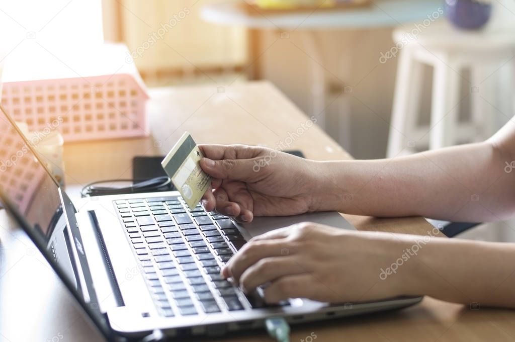 Hand holding card and using laptop for on-line shopping and payment.