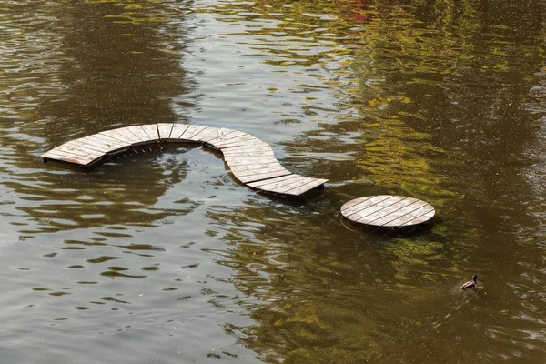 Wooden question mark on a colorful water surface