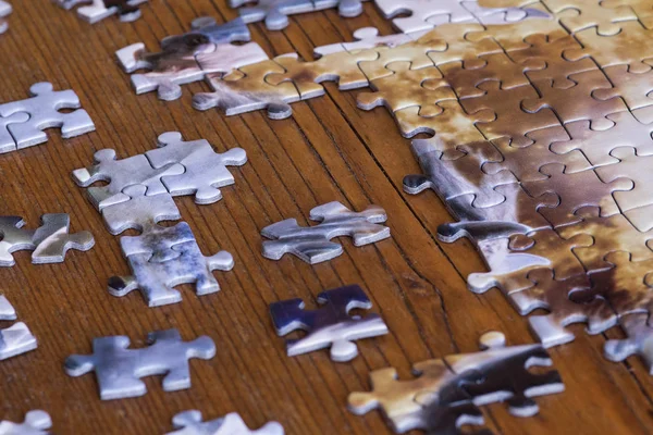 Scattered pieces of jigsaw puzzle on wooden table. Effort to fit thing together.