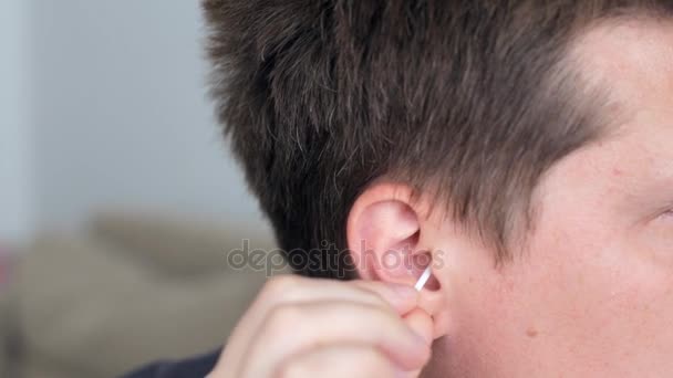 Caucásico hombre limpia su oreja con un hisopo de algodón — Vídeo de stock