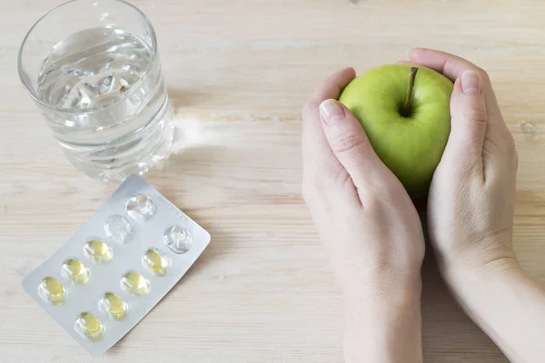 Manzana verde en manos. Un vaso de agua y pastillas. Concepto sanitario — Foto de Stock