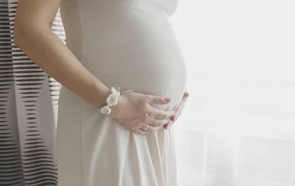 Pencerenin göbek ayakta tutan hamile kadın