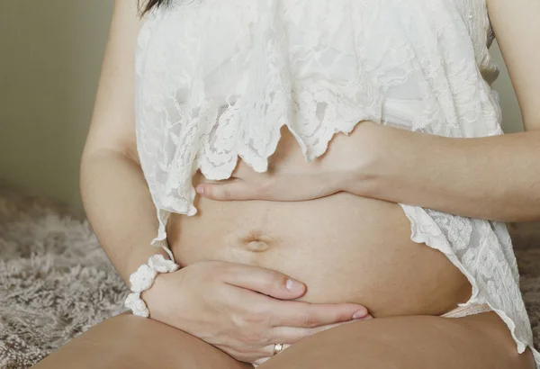 Pregnant woman holding her belly at home — Stock Photo, Image