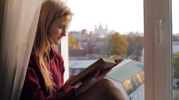 Mooie jonge vrouw leest oud boek in de buurt van het venster — Stockvideo