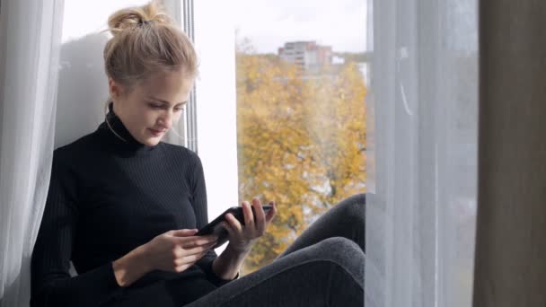 Блондинка, читающая книгу в электронном виде — стоковое видео