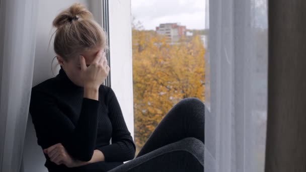 Depressief en verdrietig jongedame zittend op de vensterbank — Stockvideo