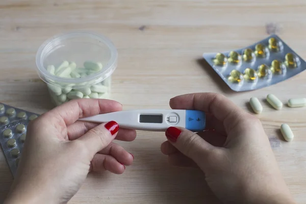 Termometre tıbbi hapları arka plan üzerinde elinde