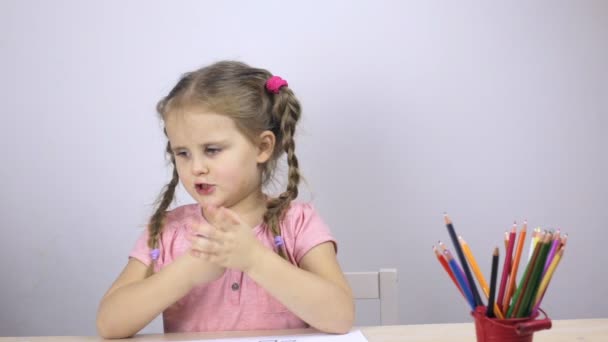 Schattig jong meisje spreekt, een blauwe potlood in de hand houden — Stockvideo