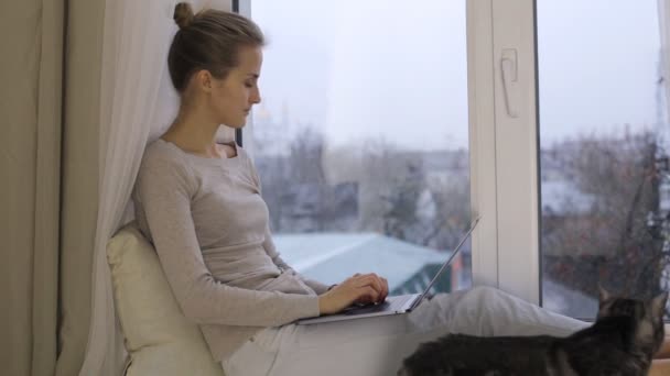 Vrouw met behulp van haar laptop zitten op de vensterbank — Stockvideo