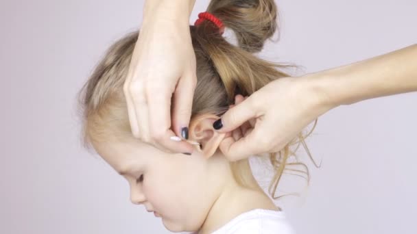 Женщина чистит своим дочерям уши ватными тампонами — стоковое видео