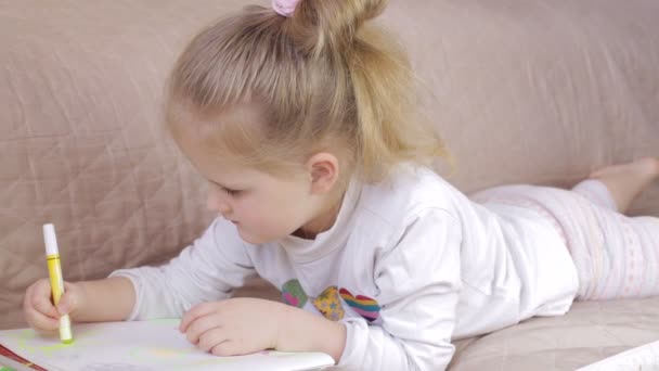 Genç kız kanepe üzerinde yalan ve çizim. Kız evde çizmek — Stok video