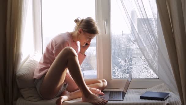 Nő beszél ő ül az ablak párkányára telefonon — Stock videók