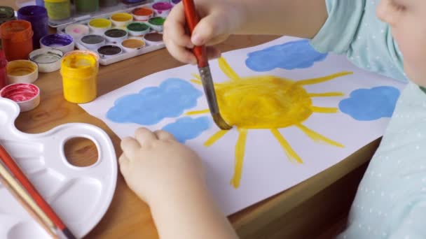 Young girl drawing yellow sun and blue clouds — Stock Video