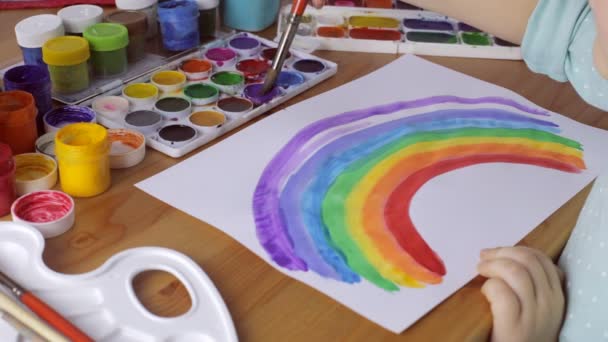 Genç kız beyaz kağıt üzerinde renkli bir gökkuşağı boyama — Stok video