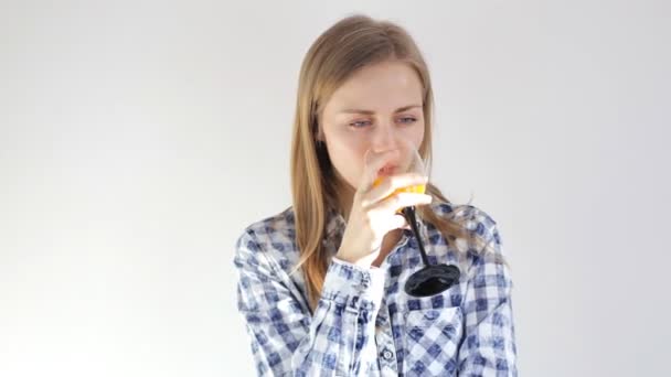 Chica bebe jugo de naranja fresco y mira a la cámara — Vídeos de Stock