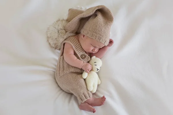Bebé recién nacido en un traje sostiene un oso —  Fotos de Stock