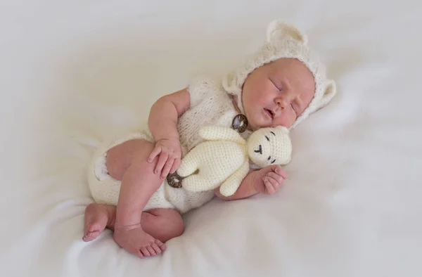 Un bebé recién nacido sostiene un osito de peluche en sus manos y duerme —  Fotos de Stock