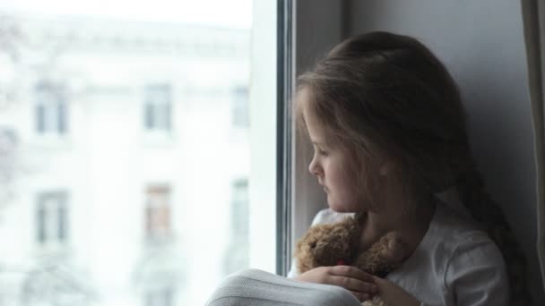 Дитина дивиться у вікно в очікуванні батьків — стокове відео