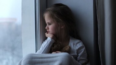 Üzgün ve yalnız çocuk bir oyuncak ayı tutuyor