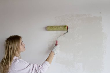 Woman enthusiastically and painstakingly paints a wall in white