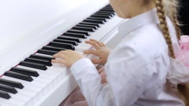 Child playing music on a white piano. The concept of playing a musical instrument