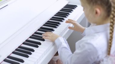 Little girl plays classical music on a piano