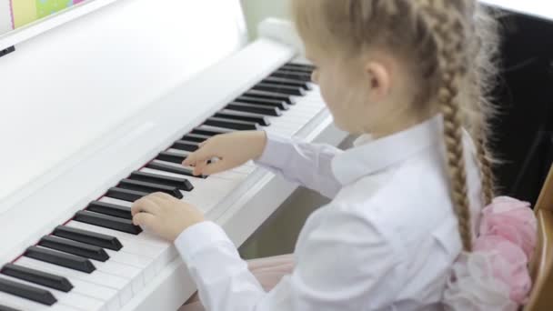 Child plays music on a white piano — Stock Video