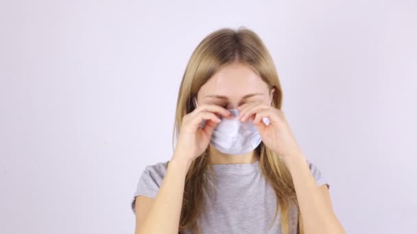 A woman in a protective medical mask rubs her eyes with her hands and looks at the camera — Stock Video