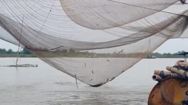 Water-level view on river chinese fishing net and fisherman using a hand net to catch fishes out of it — Stock Video