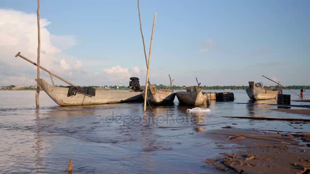 Canoe Dugout e casse di pesce in legno tengono con pali di bambù sul bordo del fiume — Video Stock