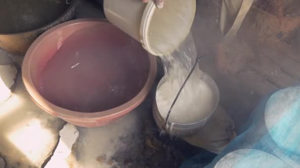 Cerca de un hombre ablandando la masa de arroz con agua en un cubo hueco — Vídeos de Stock