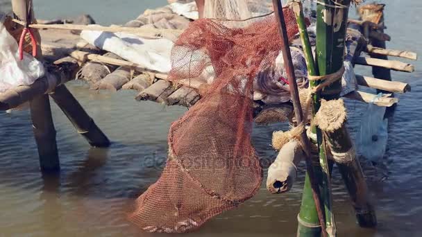 Pescador verificando sua rede em uma pequena plataforma de madeira; Peixe fresco captura rede pendurada como pano de fundo — Vídeo de Stock
