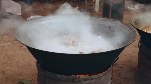 Chuletas de cerdo hirviendo en una olla grande sobre una fogata improvisada (de cerca  ) — Vídeos de Stock