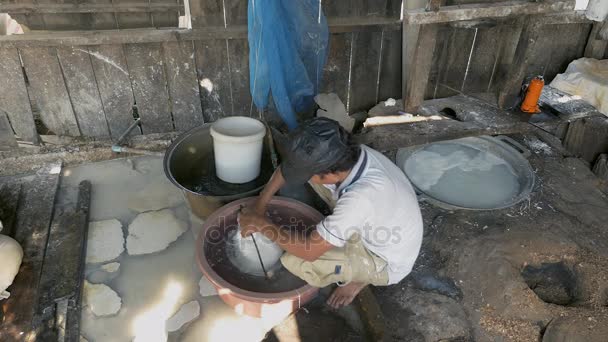 Uomo ammorbidire tagliatelle di riso con acqua in un secchio bucato prima di portarlo via — Video Stock