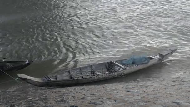 Piccola canoa da pesca scavata ormeggiata sul bordo del fiume in una giornata ventosa — Video Stock