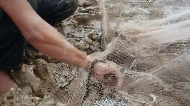 Fisherman removing enmeshed fish from his net and keeping it in a plastic bag — Stock Video