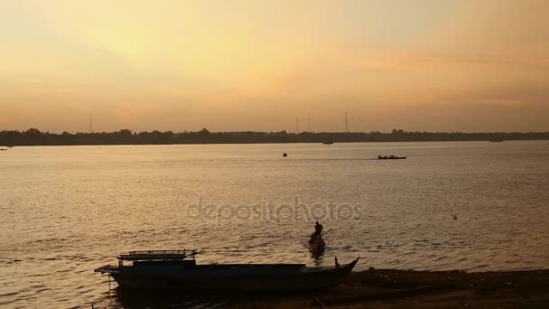 Pescador trabalhando ao nascer do sol em primeiro plano com um bando de pássaros voando sobre o rio — Vídeo de Stock